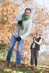 Senior couple raking leaves properly to avoid back pain